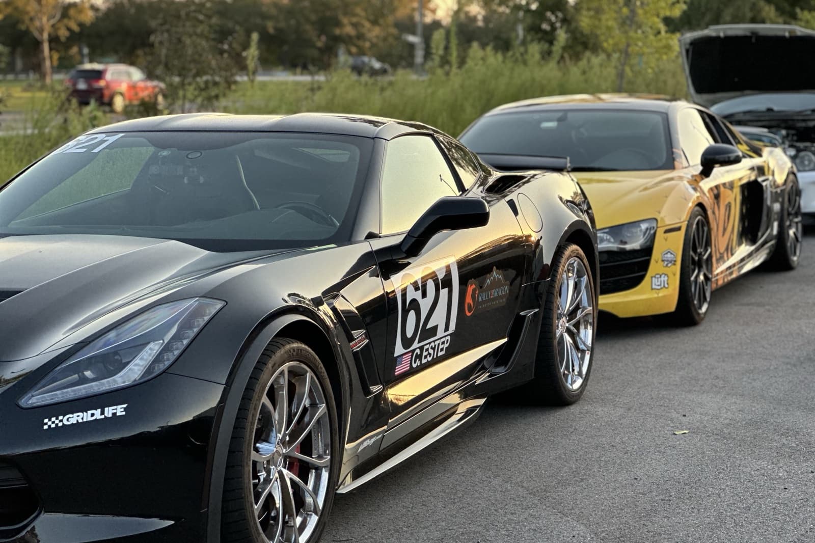 Christopher's black Corvette Grand Sport wearing Rally2Dragon decals, with an Audi R8 lined up behind it at an East Coast car meet