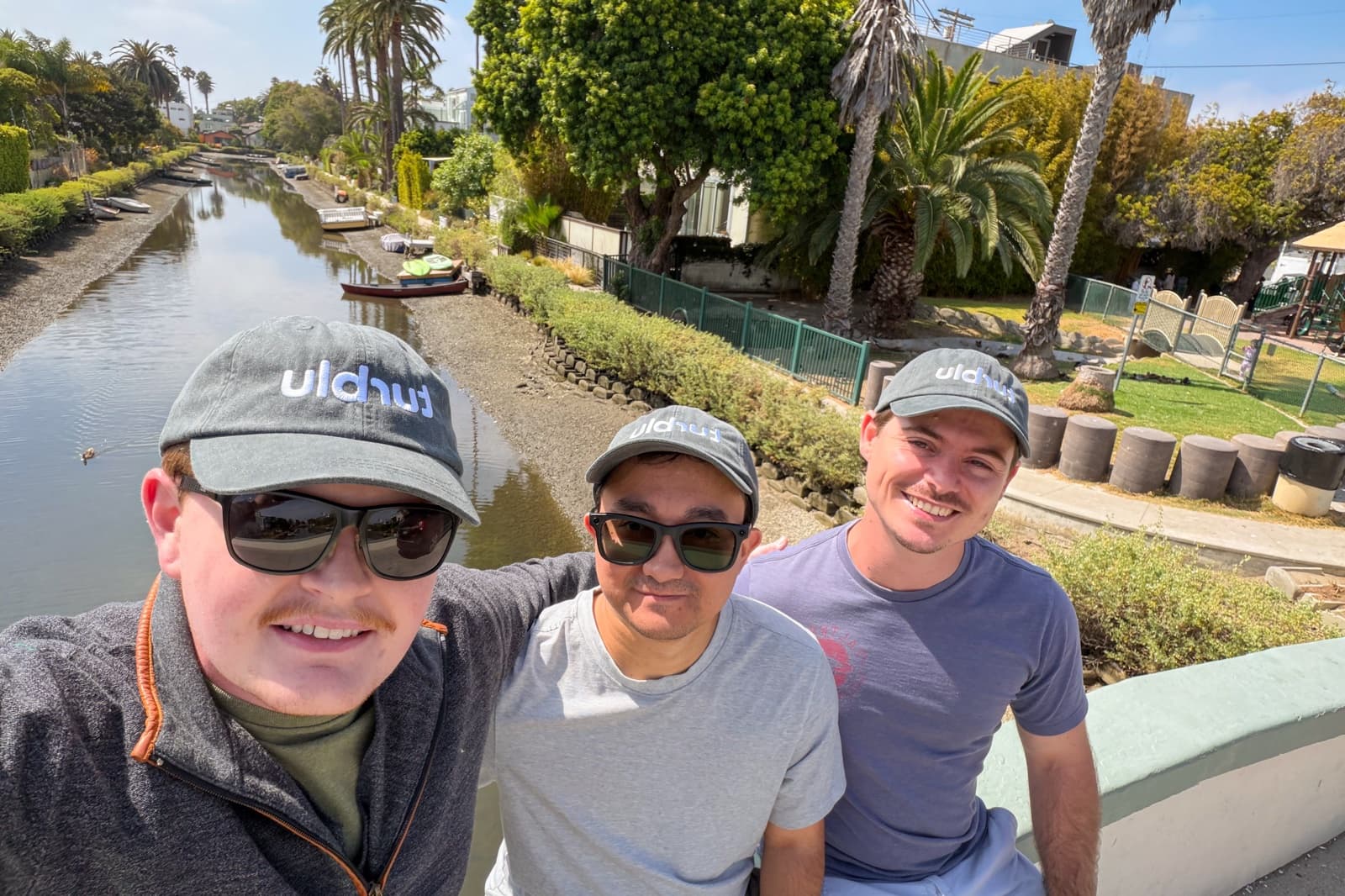 Three members of the Turblu team wearing Turblu hats on a bridge over the Venice canals